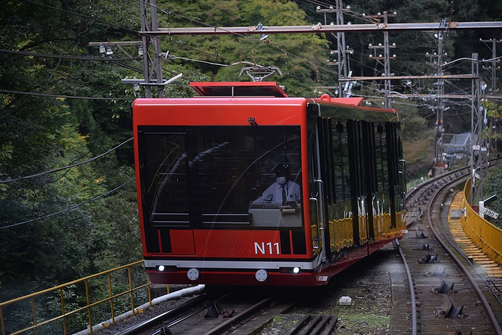 红黑色高野山缆车沿森林里的陡坡轨道上山