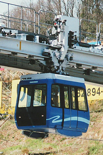 蓝色小胶囊形 Skyrail 车辆吊在上方走行机构下